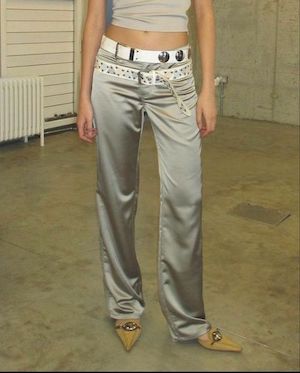 close up body shot of a woman wearing metallic pants with two white belts and gold kitten heels