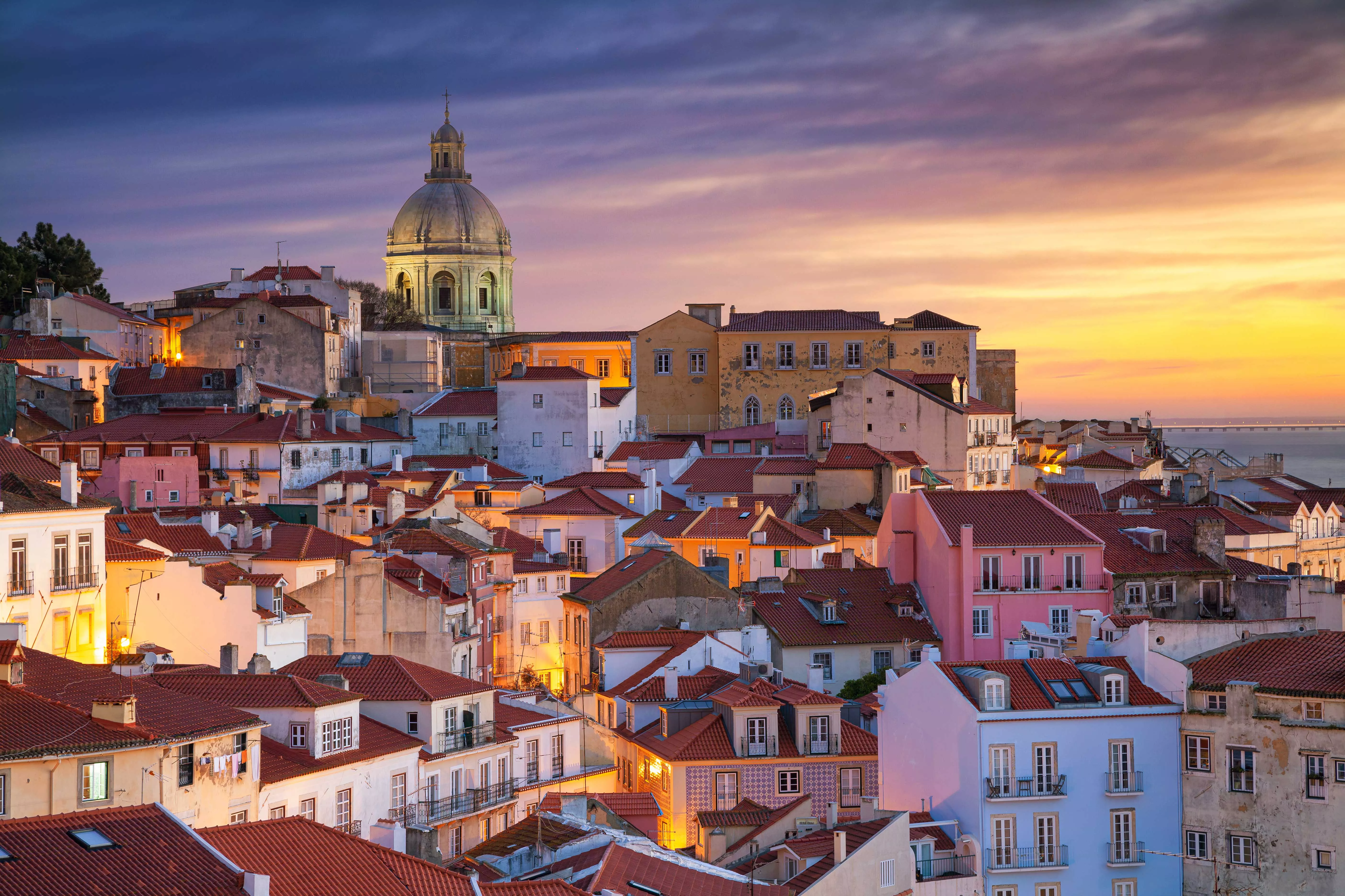 a night time portrait shot of the city of Lisbon, showing various buildings of different shapes and colors.