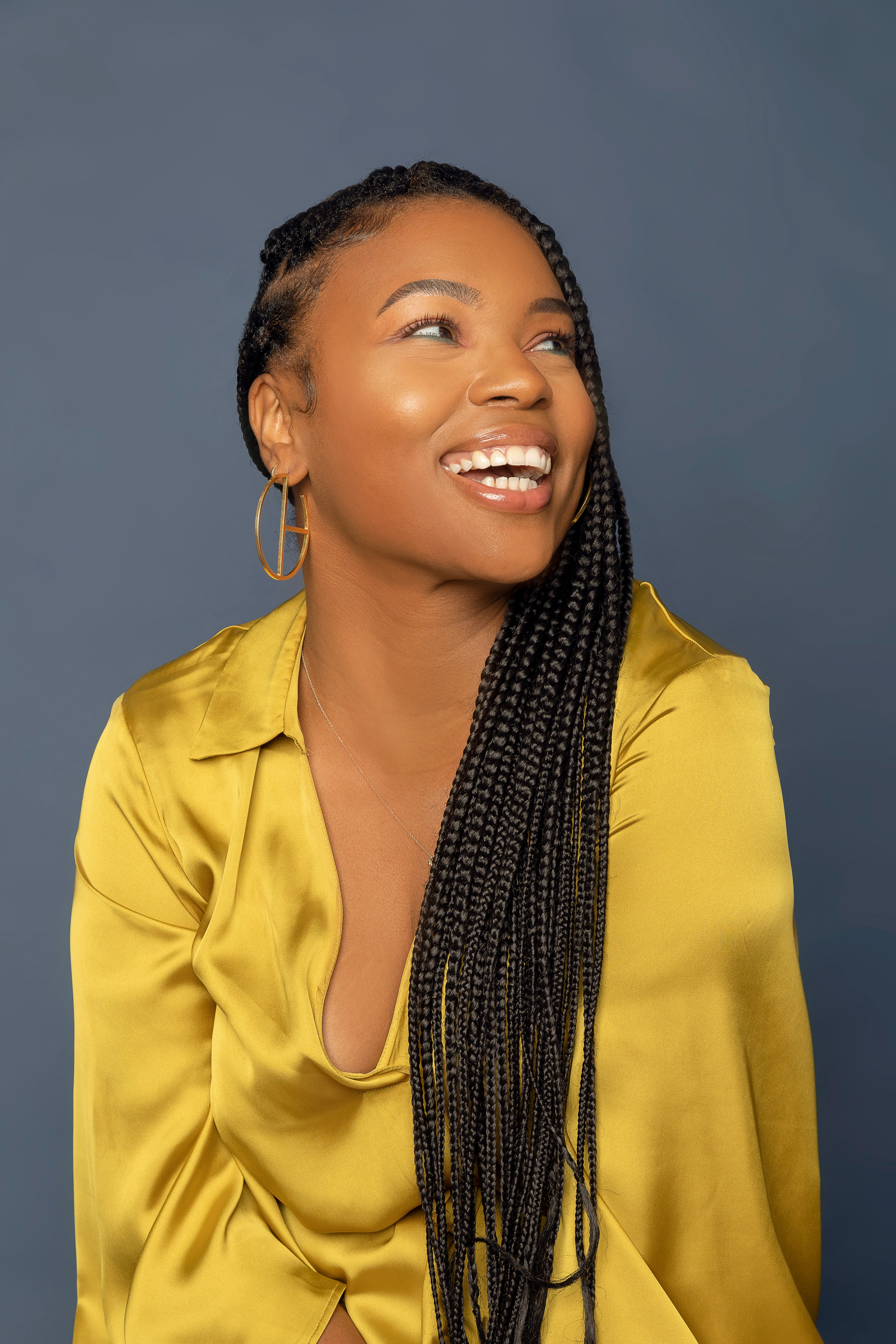 brunette woman wearing a yellow longsleeve, smiling to the right