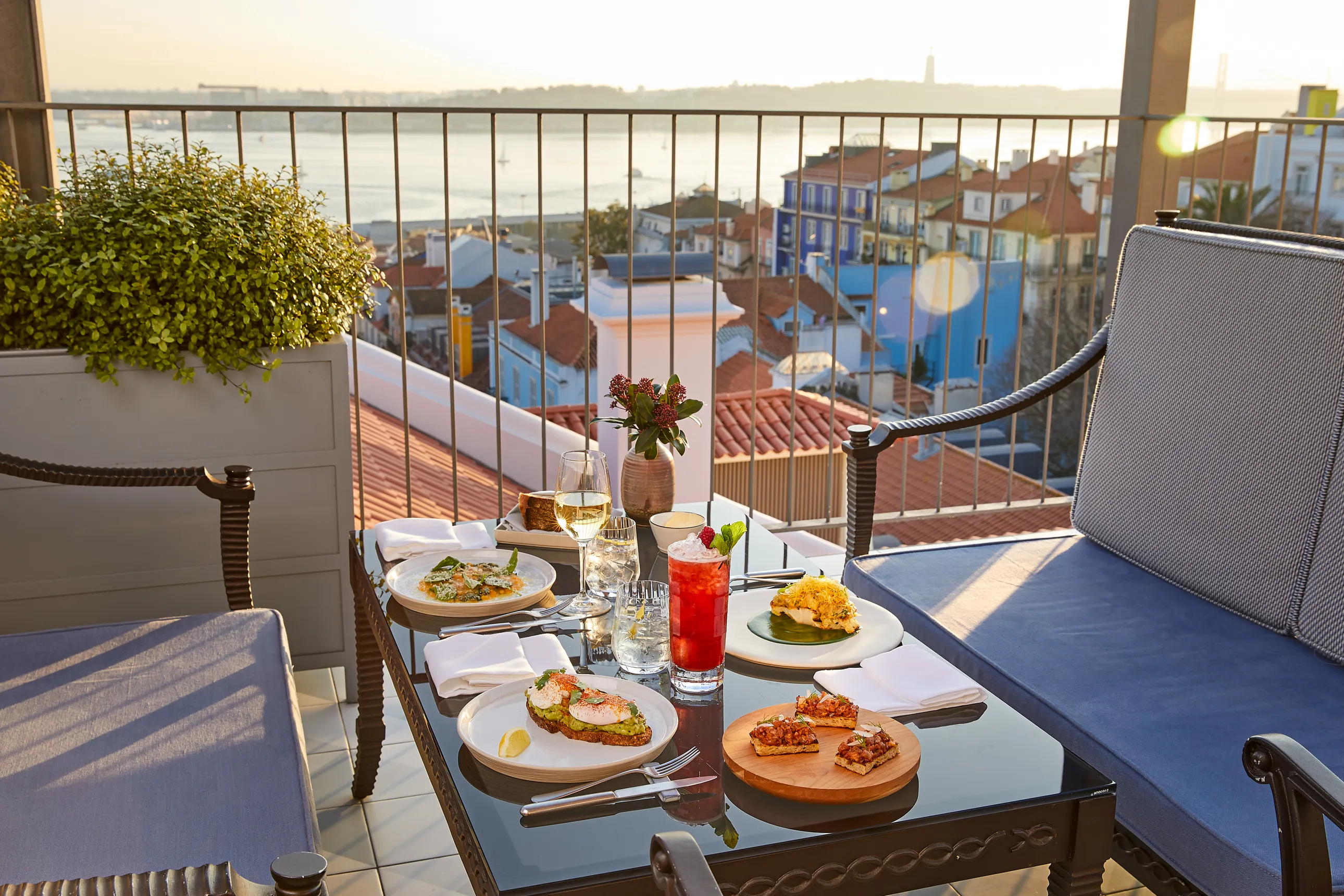 food and drinks on a table on a rooftop in Lisbon where the sun is setting