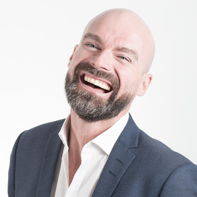 headshot of a bald man smiling with a beard in business formal