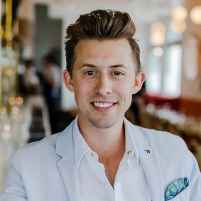 headshot of a burnette man smiling in a button up